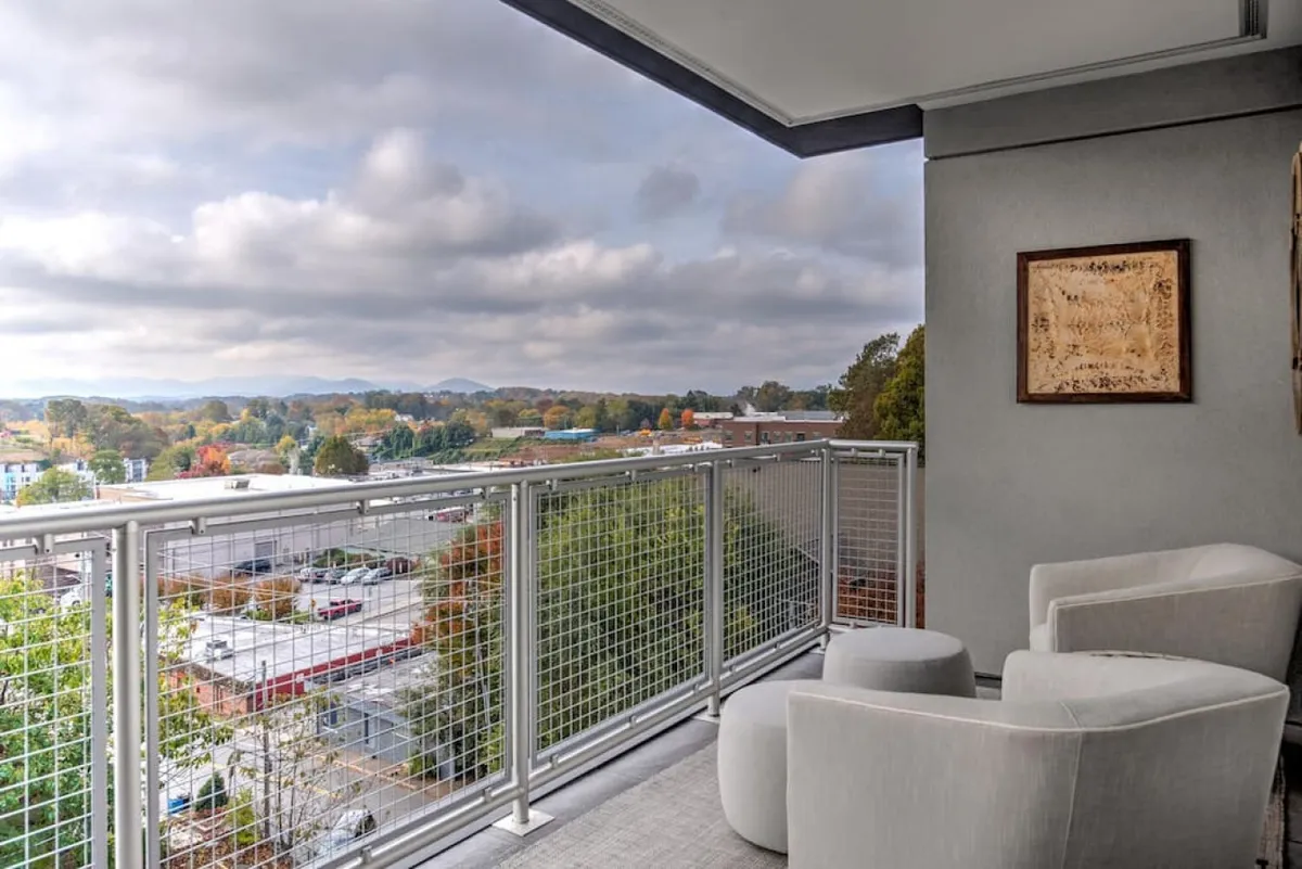 A calm, reflective scene from the balcony, featuring a seating area and a panoramic view of both the city and the surrounding mountains. The open-air environment highlights the direct connection with Asheville’s dynamic downtown while offering a peaceful retreat above the action.