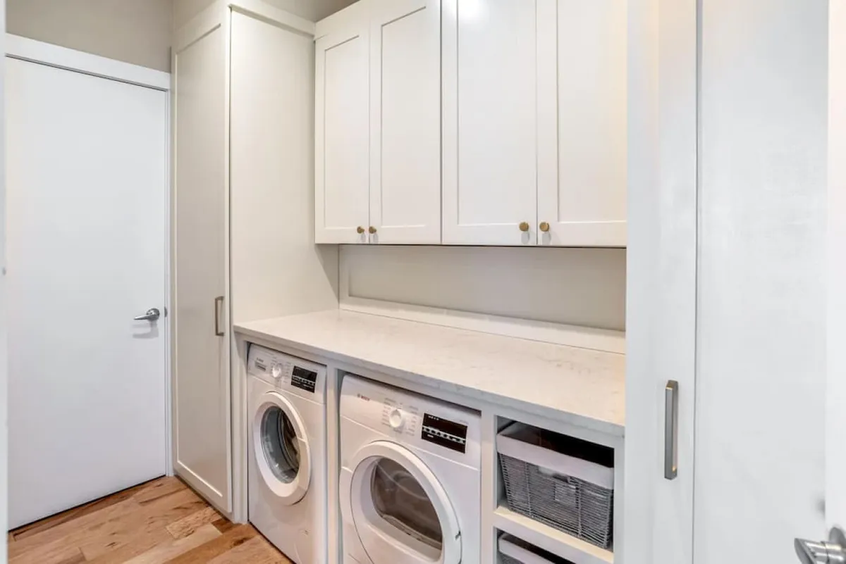 A functional laundry area with a washer and dryer, countertop space, and storage cabinets. The setup is clean, organized, and ready for families or groups needing to refresh clothes during longer stays.