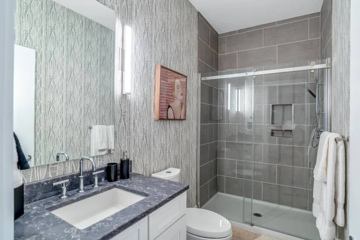 A modern bathroom featuring a sink with sleek, contemporary fixtures, an abstract artwork, and a glass shower enclosure. The space is clean and inviting, providing a spa-like atmosphere ideal for self-care and relaxation.